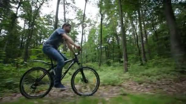 Estable cam vista del hombre montar en bicicleta en carretera forestal — Vídeo de stock