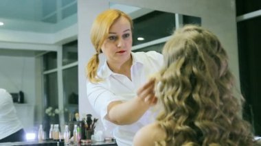 Sarışın uzun curl saç ve mavi gözleri modeli cilt için ton krem uygulayarak profesyonel makyaj sanatçısı.