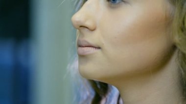 Profesyonel makyaj sanatçısı ton krem sarışın uzun curl saç ve mavi gözleri modeli cilde uygulanıyor. Yüz şekillendirme.