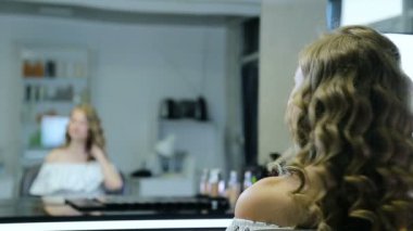 Uzun kıvırcık sarı saçlı ve mavi gözlü güzel genç kız kendini önce makyaj görünüyor