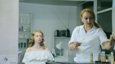 Sarışın uzun curl saç ve mavi gözleri modeli cilt için ton krem uygulayarak profesyonel makyaj sanatçısı.