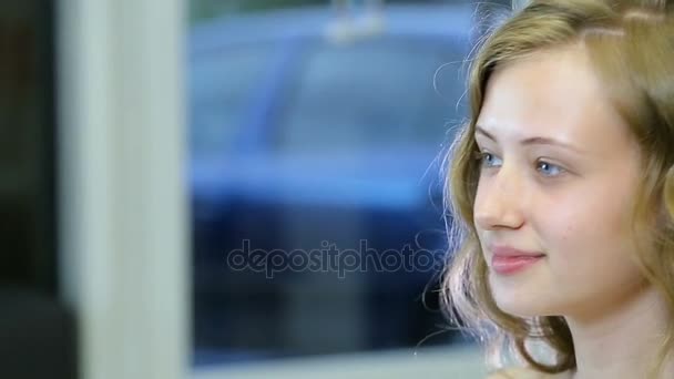 Uzun kıvırcık sarı saçlı ve mavi gözlü güzel genç kız kendini önce makyaj görünüyor — Stok video