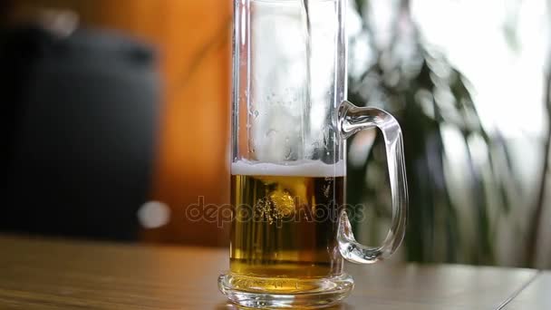 Beer is poured to half empty mug on table — Stock Video