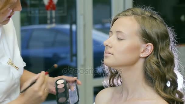 Professionele make-up artiest tonale poeder toe te passen op blond modellen ooglid. — Stockvideo