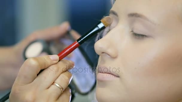 Artista de maquillaje profesional aplicando polvo tonal a modelos rubios del párpado . — Vídeos de Stock
