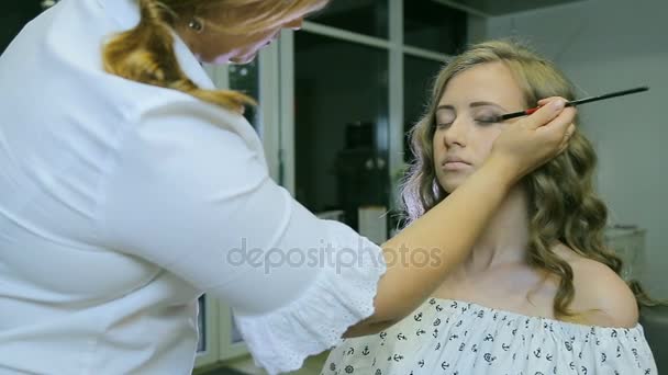 Professionelle Make-up-Artist Auftragen von Tonpuder auf blonde Models Lidschatten tun. — Stockvideo