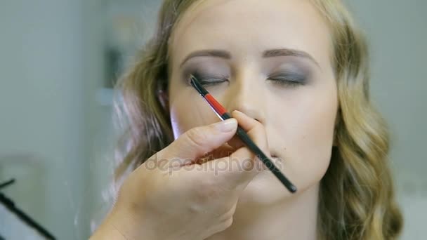 Professionelle Make-up-Artist Auftragen von Tonpuder auf blonde Models Lidschatten tun. — Stockvideo