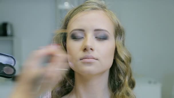 Professionelle Make-up-Artist Auftragen von Tonpuder auf blonde Models Lidschatten tun. — Stockvideo