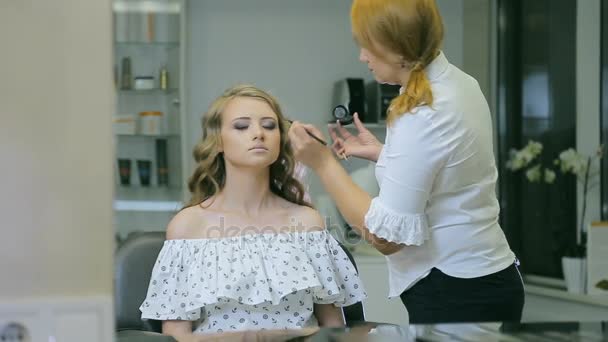Professionell makeup artist tillämpa ögonpenna och borste till blont modeller ögonlocket för att göra ögonlocket pilar. — Stockvideo