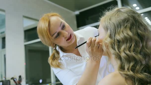 Professionele make-up artiest toepassen eye potlood en penseel naar blond modellen ooglid voor het doen van ooglid pijlen. — Stockvideo