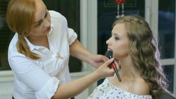 Artista de maquillaje profesional limpia la cara de la mujer con cepillo cosmético — Vídeo de stock