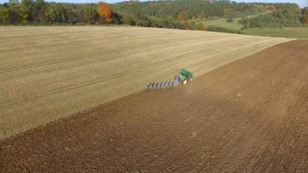 Antenn skott av traktor plöjer svart jord nära skog. Hösten sunset. — Stockvideo