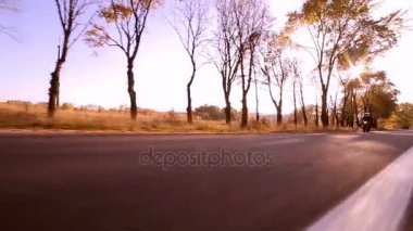 Onun motosiklet sürüş yolda günbatımı sırasında motosikletçi Steadycam atış