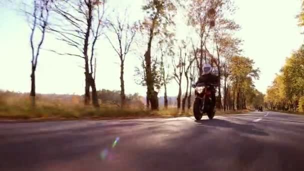 Steadycam strzał motocyklista jazda jego motocykl na drodze podczas zachodu słońca — Wideo stockowe