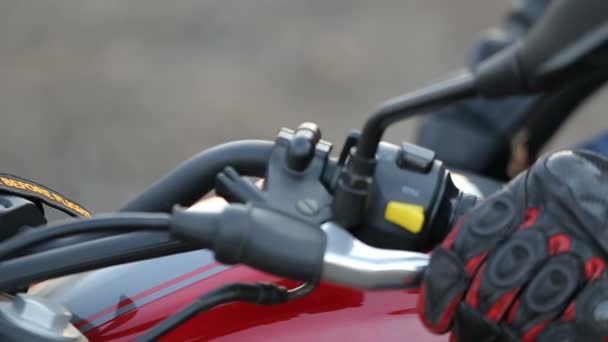 A young man in black leather jacket and white helmet sits on motorcycle turns key before journey at autumn sunset — Stock Video