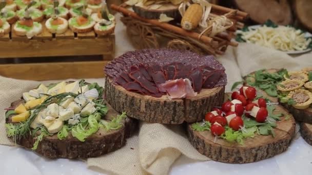 O basturma de carne e os lanches de queijo em chapas de madeira põem-se em uma mesa — Vídeo de Stock