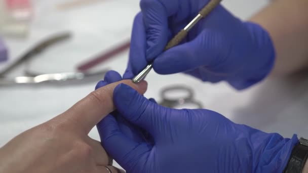 Професійний манікюрник в рукавичках готує шкіру нігтів перед покриттям лаком . — стокове відео