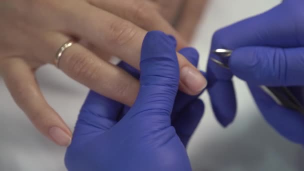Professionell manikyrist i handskar som skär av huden på naglarna innan de täcker med lack. Närbild skott. — Stockvideo