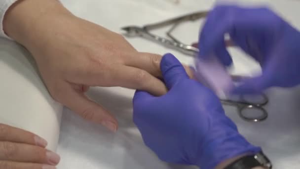 Professional manicurist in gloves polishing fingernails before covering with varnish. — Stock Video