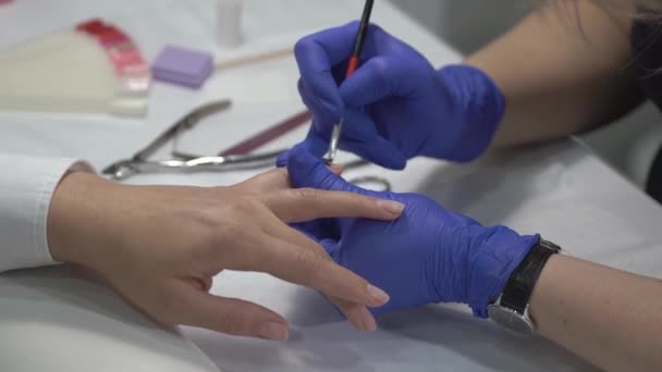 Manicura profesional en guantes que cubren las uñas al principio antes de cubrirlas con barniz . — Vídeos de Stock