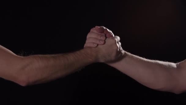 Мужчины Кавказа пожимают друг другу руки на черном фоне, закрываются в изоляции — стоковое видео