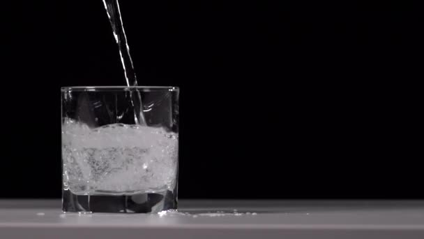 Студійний Знімок Води Вливається Прозоре Скло Білому Столі Чорному Тлі — стокове відео