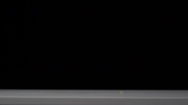 Beyaz masaya düşen fıstıkların süper yavaş çekimi. Siyah arkaplan.