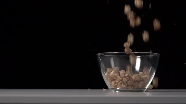 甜而蓬松的焦糖爆米花倒入白色桌子上透明的班级碗里 黑色背景 超级慢动作 — 图库视频影像