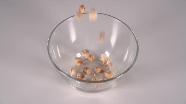 白いテーブルの上に透明なクラスボウルに注ぐ甘いふわふわのキャラメルポップコーン 黒の背景 超スローモーション — ストック動画