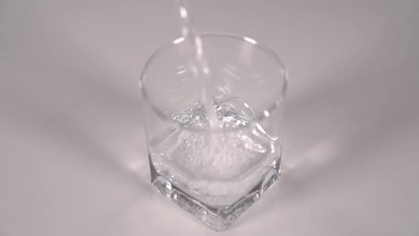 Plan studio d'eau coulant dans du verre transparent sur une table blanche. Super ralenti .