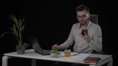 Dizüstü bilgisayarda çalışırken sakallı genç işadamı telefon alıyor, laptopu kapatıyor ve işten çıkıyor..
