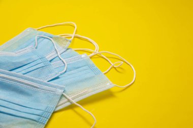 Sarı arka planda enfeksiyonu önlemek için tek kullanımlık mavi tıbbi maskeler. Salgın COVID19 kavramı için kullanışlı
