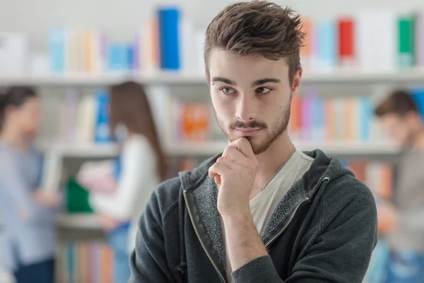 Vertrouwen mannelijke student poseren in bibliotheek — Stockfoto