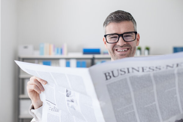 Confident businessman reading a newspaper