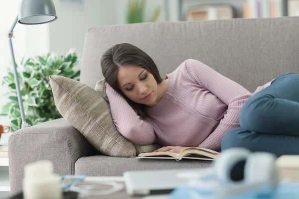 Flicka som läser en bok i soffan — Stockfoto