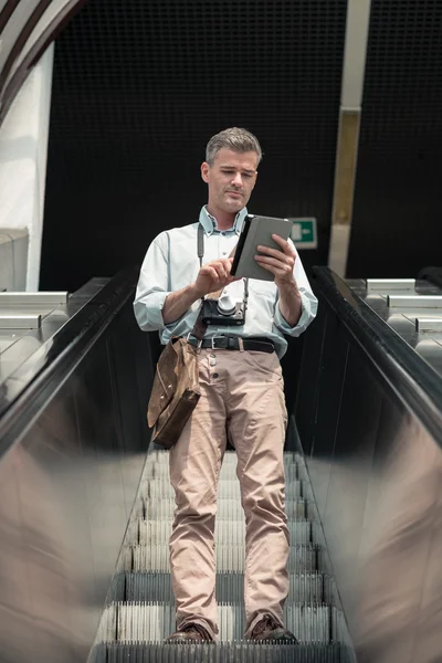 Mannen på rulltrappan använder en surfplatta — Stockfoto