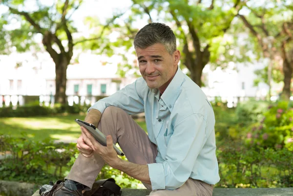 Чоловік у парку використовує планшет — стокове фото