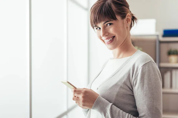 Mujer atractiva alegre usando un teléfono móvil —  Fotos de Stock