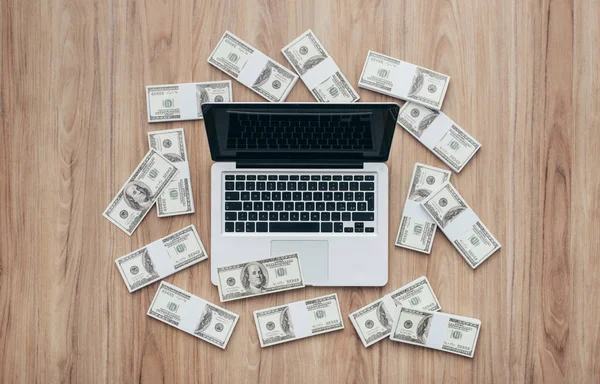 Laptop circondato da un carico di denaro contante — Foto Stock