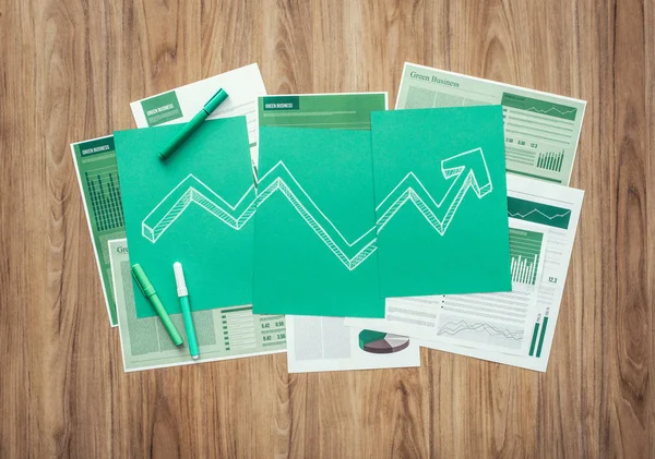 Chart with arrow on green sheets and paperwork — Stock Photo, Image
