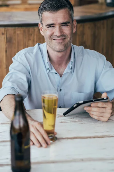 Человек с помощью планшета и питьевого пива — стоковое фото