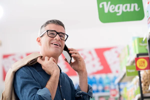 Homem a fazer um telefonema no supermercado — Fotografia de Stock