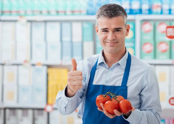 Supermarkt klerk bedrijf tomaten — Stockfoto