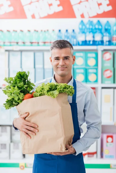 Shop assistant holding grocery bag — Stock Photo, Image