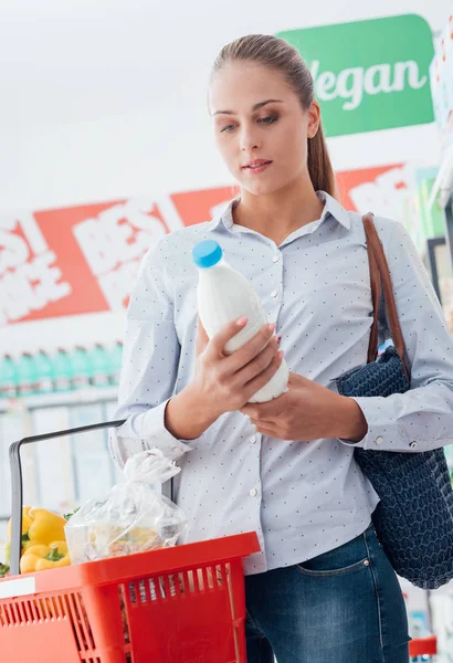 Mulher lendo rótulo alimentar em garrafa — Fotografia de Stock