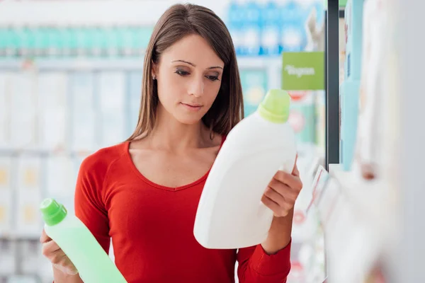 Mulher comparando produtos detergentes — Fotografia de Stock