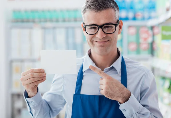 Trabalhador de supermercado titular de cartão em branco — Fotografia de Stock
