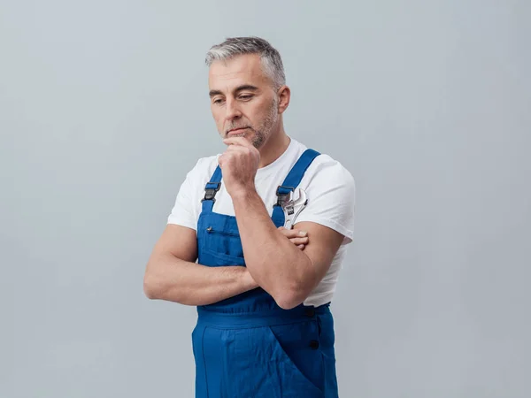 Reparador con la mano en la barbilla y la llave inglesa — Foto de Stock