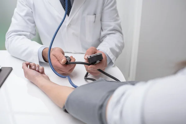 Läkaren kontrollerar blodtryck av patient — Stockfoto