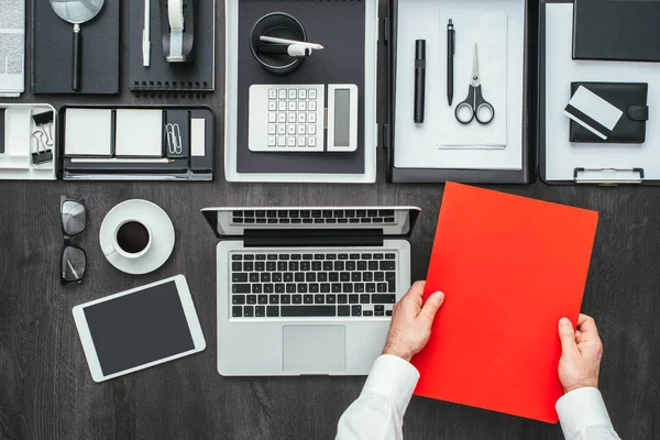 Empresario sosteniendo carpeta roja en el escritorio —  Fotos de Stock